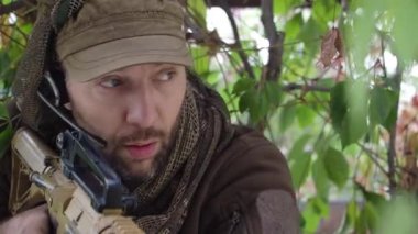 Görevdeki bir asker. Ormanda yavaşça ilerleyip düşmanı takip ediyor. Yakın çekim videosu.