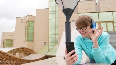 Mavi kulaklıklı genç kadın blogcu açık havada yayın yapıyor ve olaylar hakkında konuşuyor..