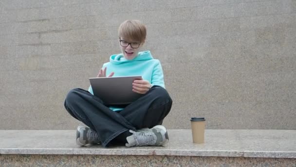온라인 비디오 통화중 한 젊은 여성 블로거입니다. 그녀는 노트북을 들고 야외에 앉아서 친구들 과 이야기를 나누고 있습니다. — 비디오