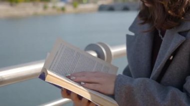 Kafkasyalı kadın ellerinin kitabı tuttuğu yakın plan. Güneşli bir günde kitap okuyan tanınmayan bir kadın..