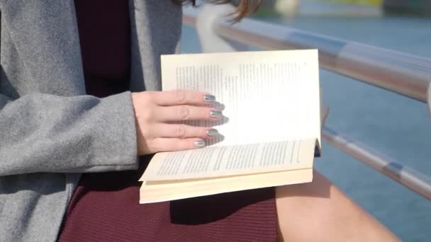 Weibliche Hände halten Buch. Unerkennbare Frau liest Buch an sonnigem Tag im Freien. — Stockvideo