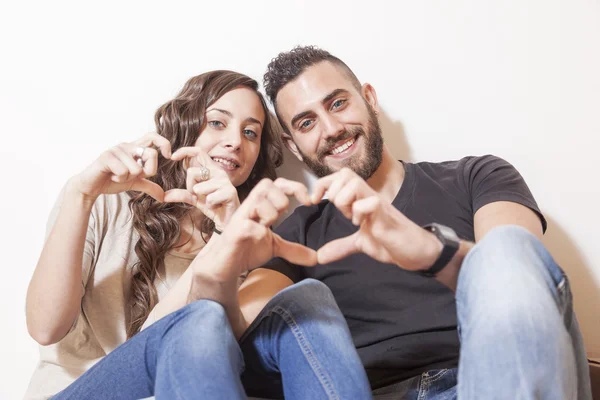 Bonito jovem casal faz sinal de coração com as mãos — Fotografia de Stock