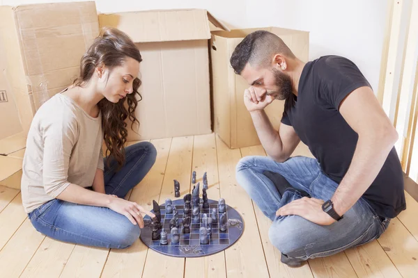 Молодая пара играет в шахматы после переезда — стоковое изображение Молодая пара играет в шахматы после переезда — стоковое фото