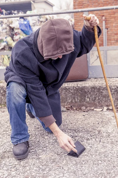 Daklozen vindt een portefeuille van de vloer in de stortplaats — Stockfoto