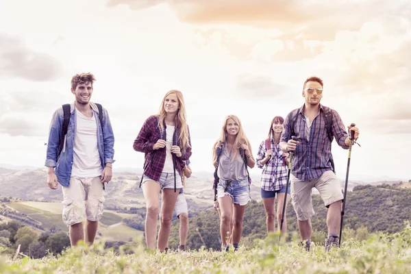 Skupina mladých turistů vypadá na obzoru nad horou — Stock fotografie