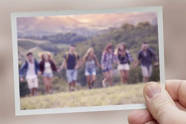 Hand hält Schnappschuss von Wandergruppe im Berglauf — Stockfoto