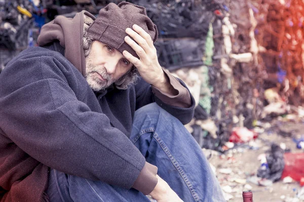Homeless man with a bottle of red wine in landfill — Stock Photo, Image