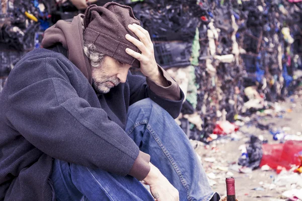 Homeless man with a bottle of red wine in landfill — Stock Photo, Image