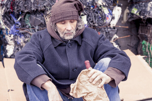 homeless man with a bottle of red wine in landfill