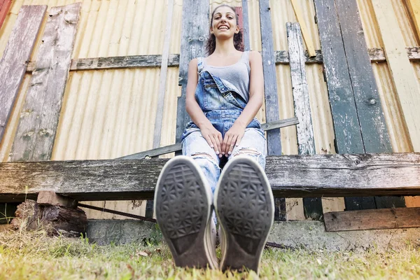 Jovem menina bonita sentada no parque com os pés em primeiro plano — Fotografia de Stock