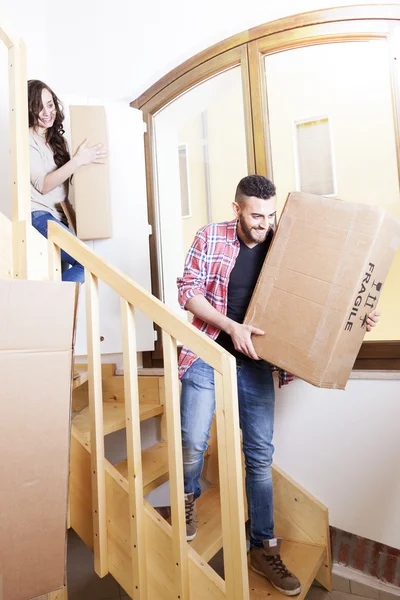 Pareja joven llevando las cajas en casa nueva — Foto de Stock