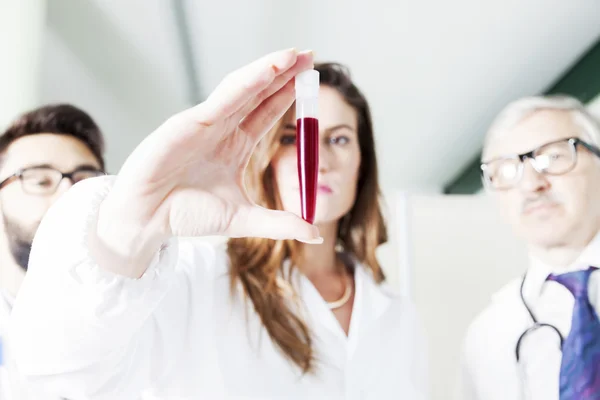 Médicos jóvenes examinan el tubo sanguíneo en el laboratorio —  Fotos de Stock