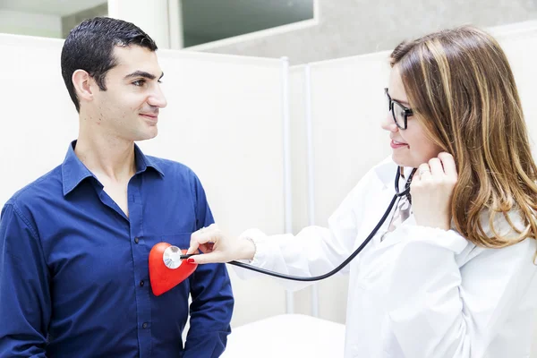 Female doctor listens to the heartbeat of a patient — Stock Photo, Image