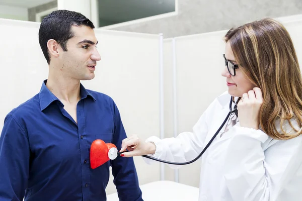 Female doctor listens to the heartbeat of a patient — Stock Photo, Image