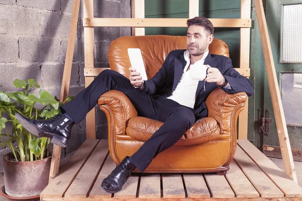 Young businessman sitting in his chair watching smart phone — Stock Photo, Image