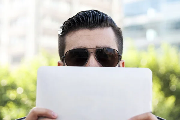 Jovem hipster empresário segurando o laptop na frente da cara — Fotografia de Stock