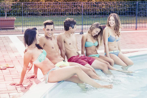 Groupe de jeunes amis assis près de la piscine — Photo