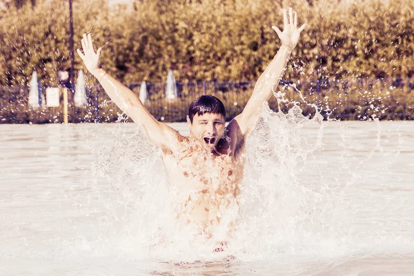 Bel homme amusez-vous dans la piscine avec des éclaboussures d'eau — Photo