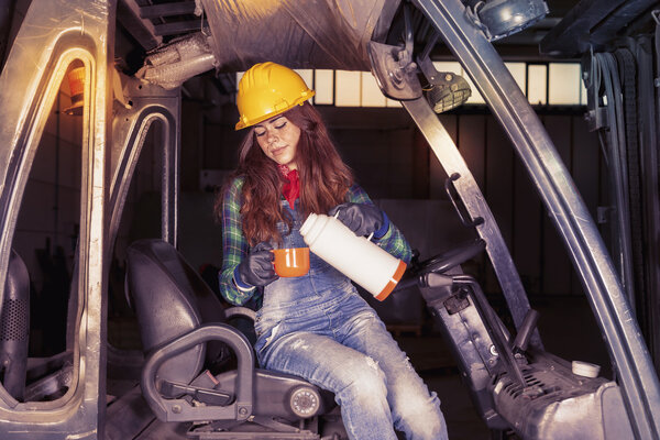 portrait of a worker young girl on coffee break on a forklift