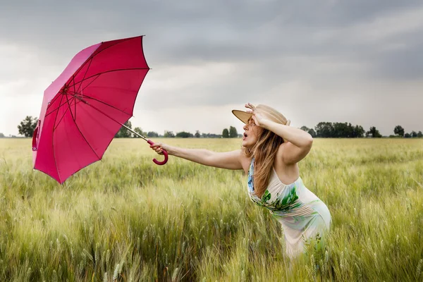 Pretty woman with umbrella in a field of wheat ears — Stock Photo, Image