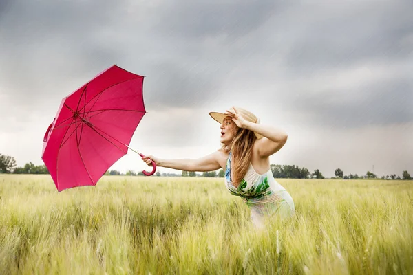 Bonita mujer con paraguas en un campo de espigas de trigo — Foto de Stock