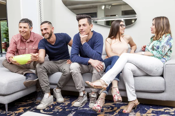 Gruppo di amici guardando la tv e mangiando popcorn sul divano — Foto Stock