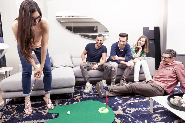 Grup genç yetişkin oturma odasında golf oynarken iyi eğlenceler