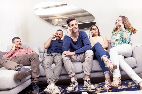 Группа друзей на диване к телефону в то же время — стоковое фото