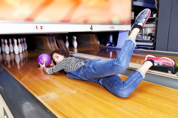 Jeune femme glissant sur une piste de bowling — Photo