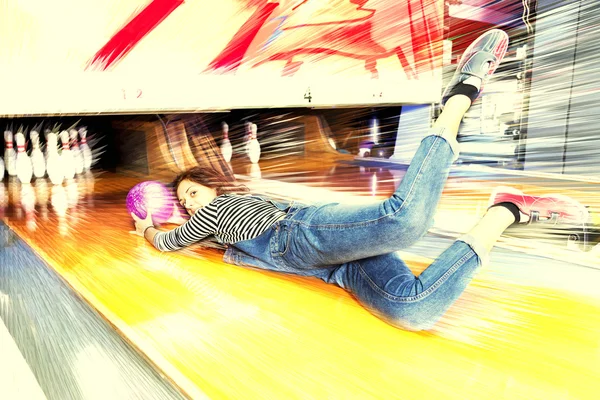 Jovem mulher deslizando para baixo uma pista de boliche — Fotografia de Stock