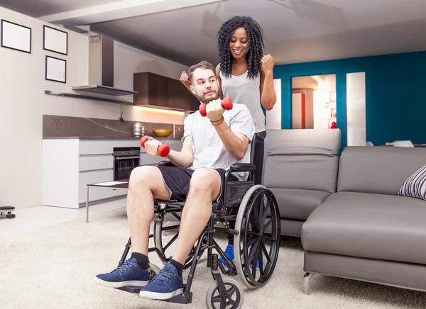 Young girl helps a disabled to rised dumbbells — Stock Photo, Image