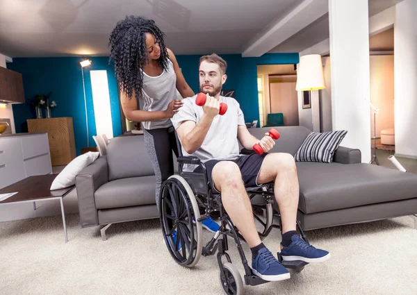 Jeune fille aide un handicapé à monter haltères — Photo