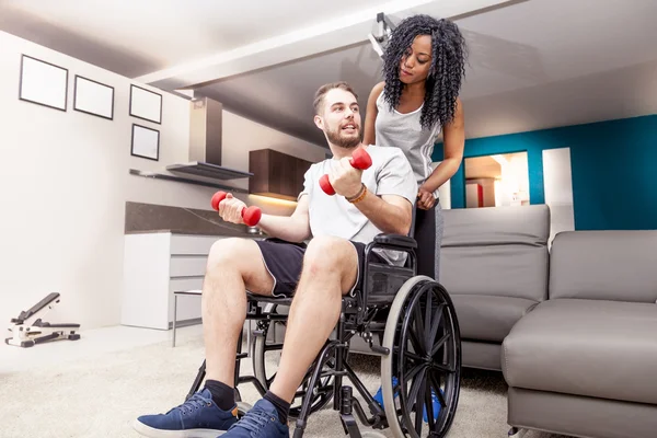 Jeune fille aide un handicapé à monter haltères — Photo