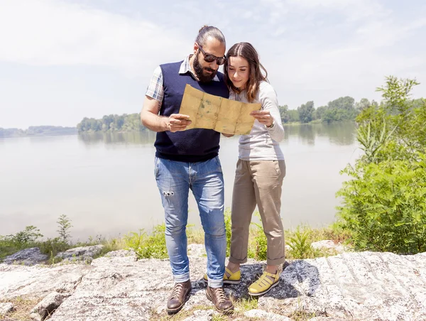 Jovem casal de amantes consulta um mapa ao ar livre — Fotografia de Stock