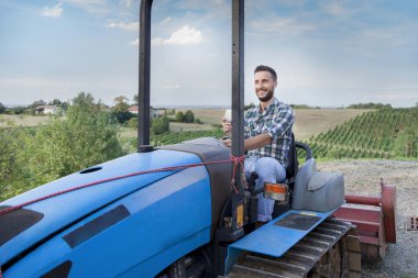 young farmer toasts on a crawler tractor in his vineyard clipart