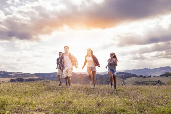 Gruppe junger Wanderer rennt über den Berg dem Horizont entgegen — Stockfoto