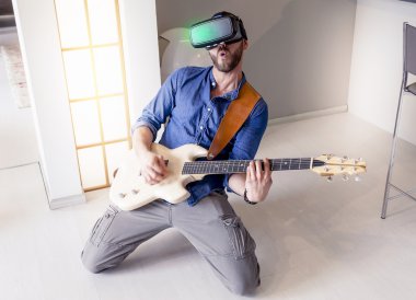 Genç Yetişkin evde gitar çalmak için sanal gerçek Görüntüleyicisi'ni kullanma