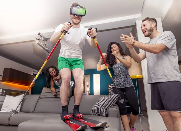 Grupo de amigos divirtiéndose en casa esquiando usando visor para virt — Foto de Stock