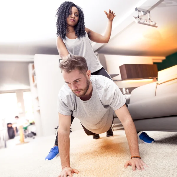 Jovem casal se divertindo fazendo ginástica em casa — Fotografia de Stock