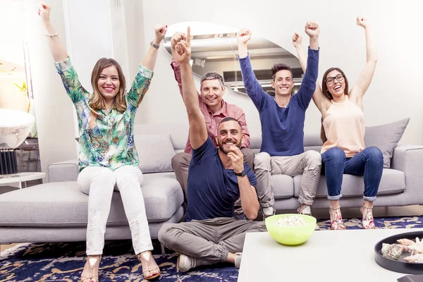 group of friends watching a football match on tv on the couch