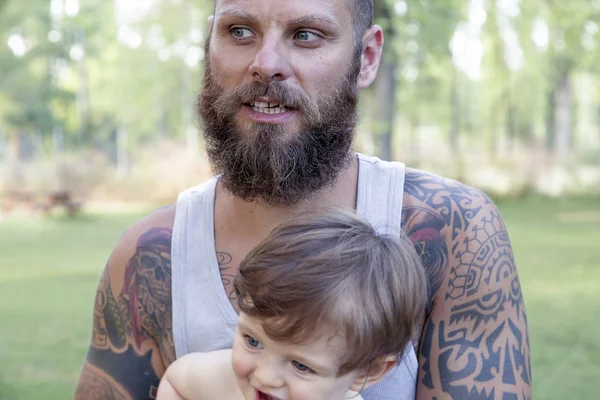 Татуированный отец веселится со своим сыном в парке — стоковое фото