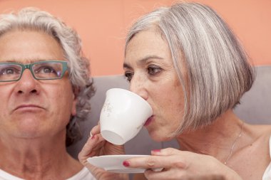 oldukça olgun çift yatakta breakfas yerken eğleniyor