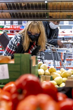 Çok ırklı bir çift, Coronavirus acil döneminde süpermarkette yüz maskesi takıyor.