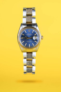 CREMONA, İtalya - 2021 OCAK: Sarı arka planda Rolex Oyster Blue saati. Rolex SA, 1905 yılında Londra 'da kurulan İsviçre' nin en lüks saat üreticilerinden biridir.