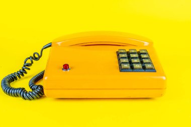 Sarı arka planda kırmızı düğmeli sarı plastik telefon.