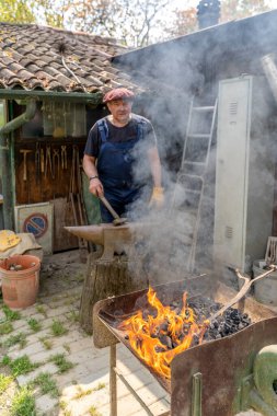 Demirci yeni bir şekil vermek için metal bir çubuk yakıyor. Eski çalışma konsepti