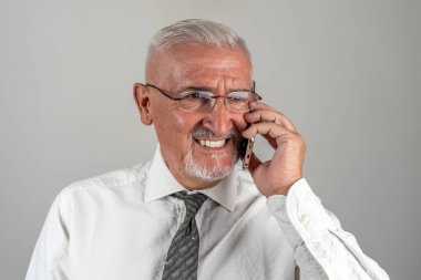 Gülümseyen iş adamının portresi gri arka planda izole edilmiş akıllı bir telefonla arıyor.