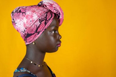 Sarı arka planda izole edilmiş kafasında renkli etnik eşarp olan Afrikalı kadın portresi