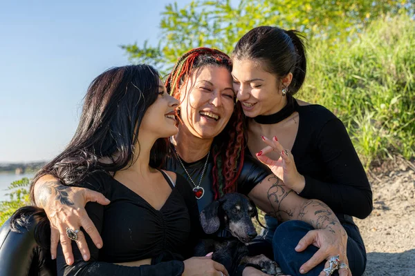 Üç kadın ve köpekten oluşan mutlu bir aile birlikte eğleniyor, gülüyor ve kaynaşıyorlar.