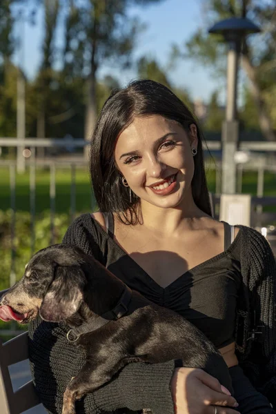 Gülümseyen kadın sevgili köpeğini parkın dışında güneşli bir günün tadını çıkarıyor.